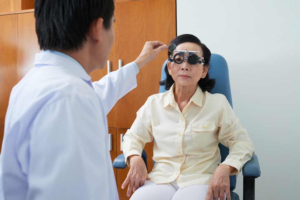 Ophthalmologist examining eyesight of senior patient with special medical device in hospital