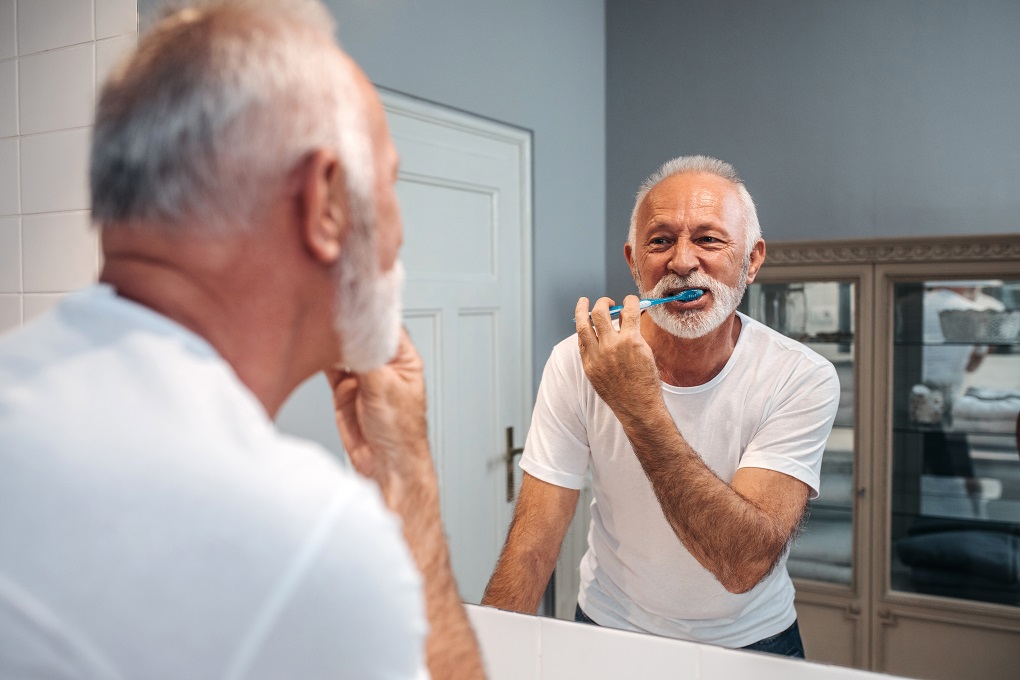 Senior man brushing his teeth in bathroom