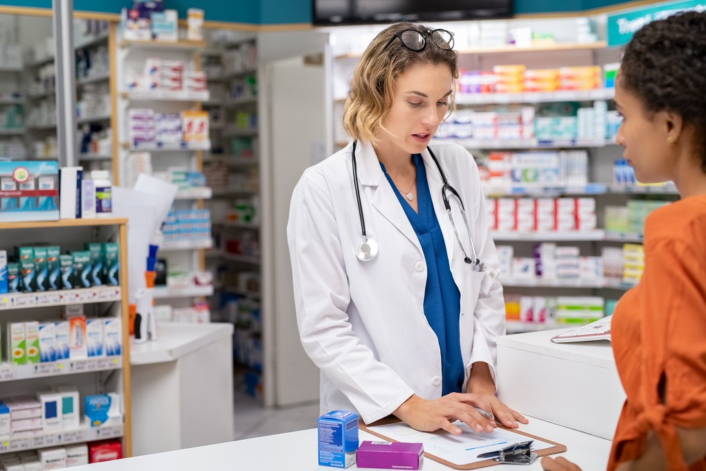 Pharmacist giving medicine with prescription to customer